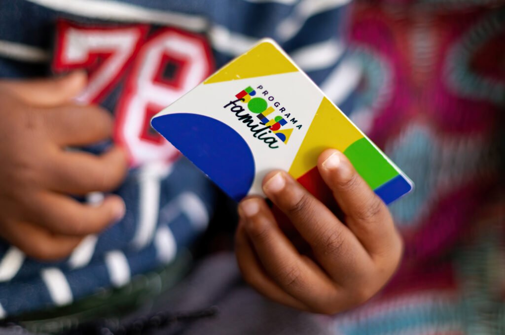 Criança segura o cartão do programa Bolsa Família, que paga em outubro o primeiro mês com reajuste de 15%