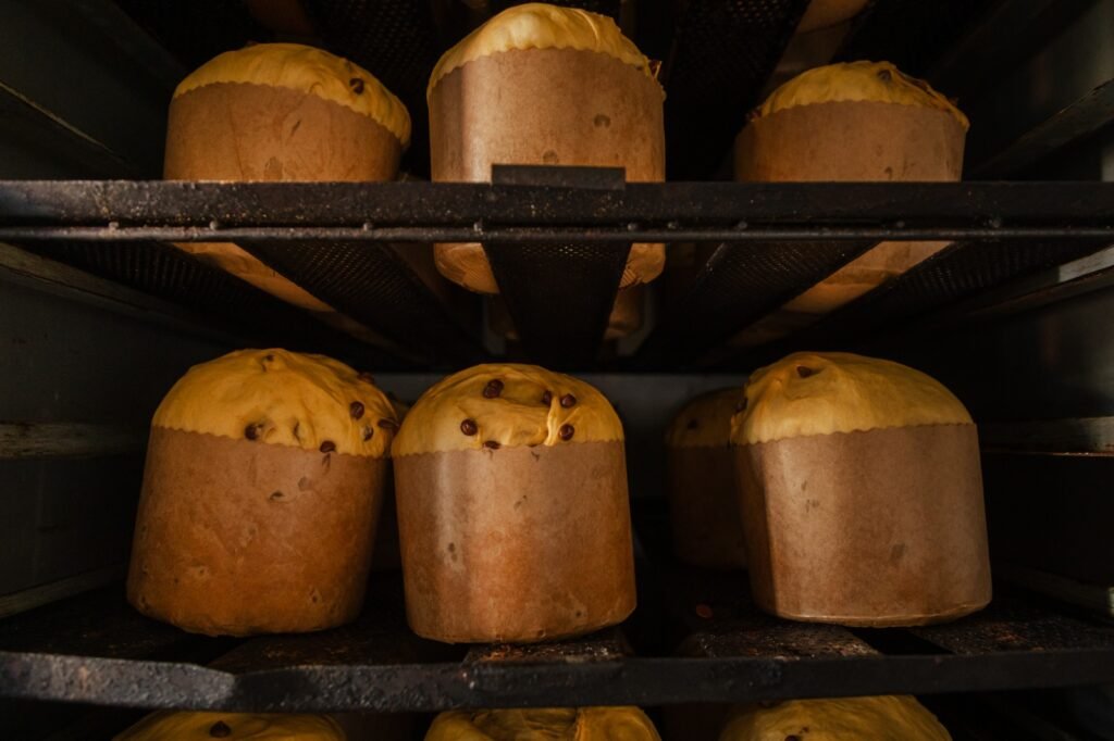Panetones em assadeiras durante preparo em forno de panificação