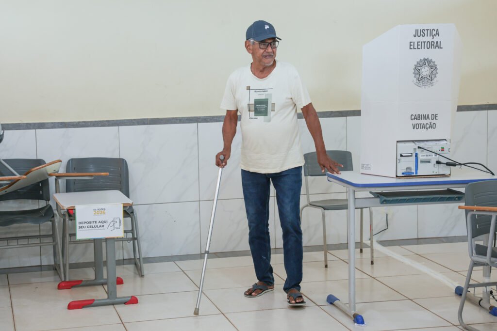 Segundo turno em Goiás: eleitor caminha com bengala em seção eleitoral, ao lado da cabine de votação da Justiça Eleitoral