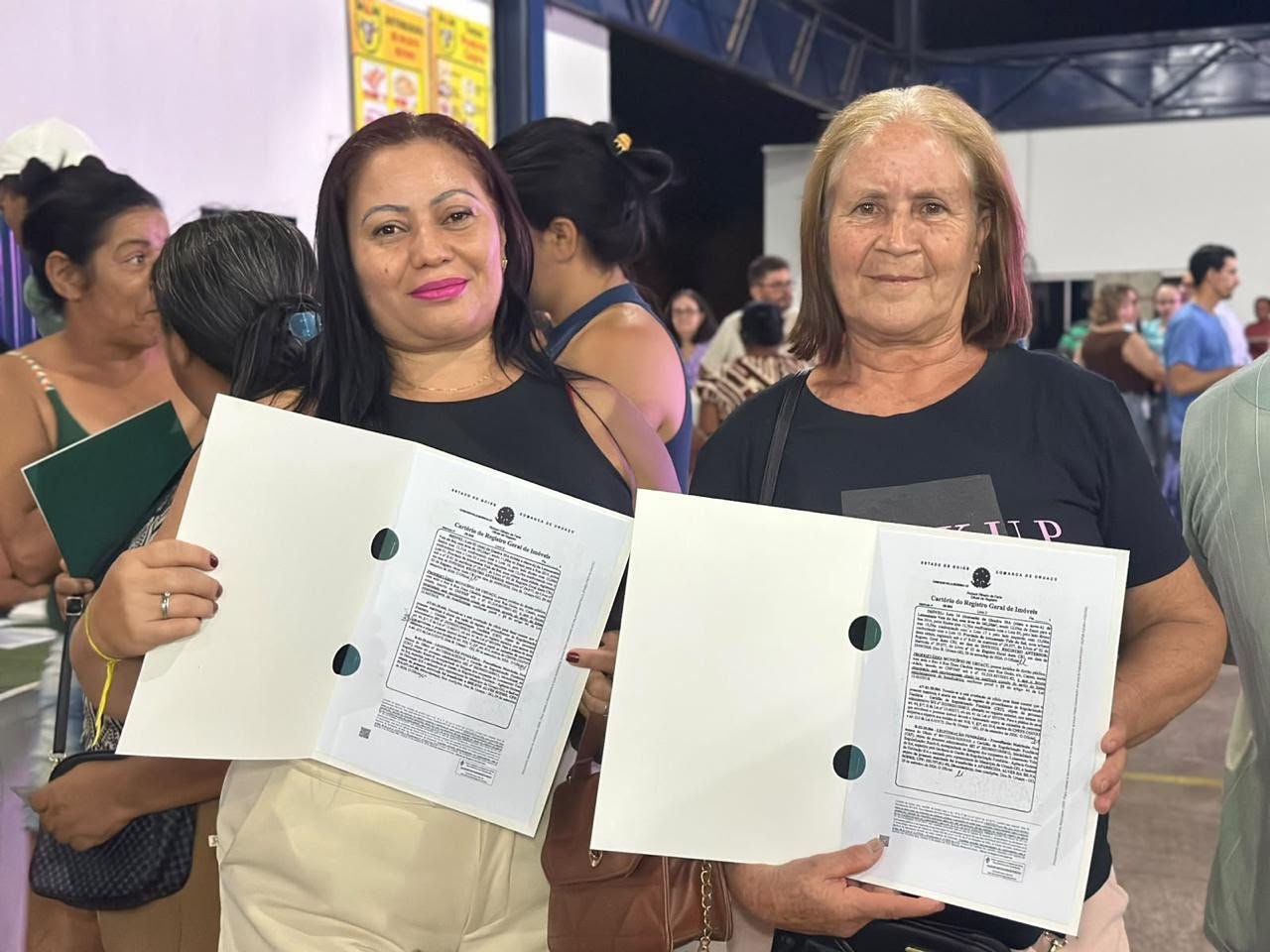 Duas moradoras mostram as escrituras de suas casas entregues pela Agehab