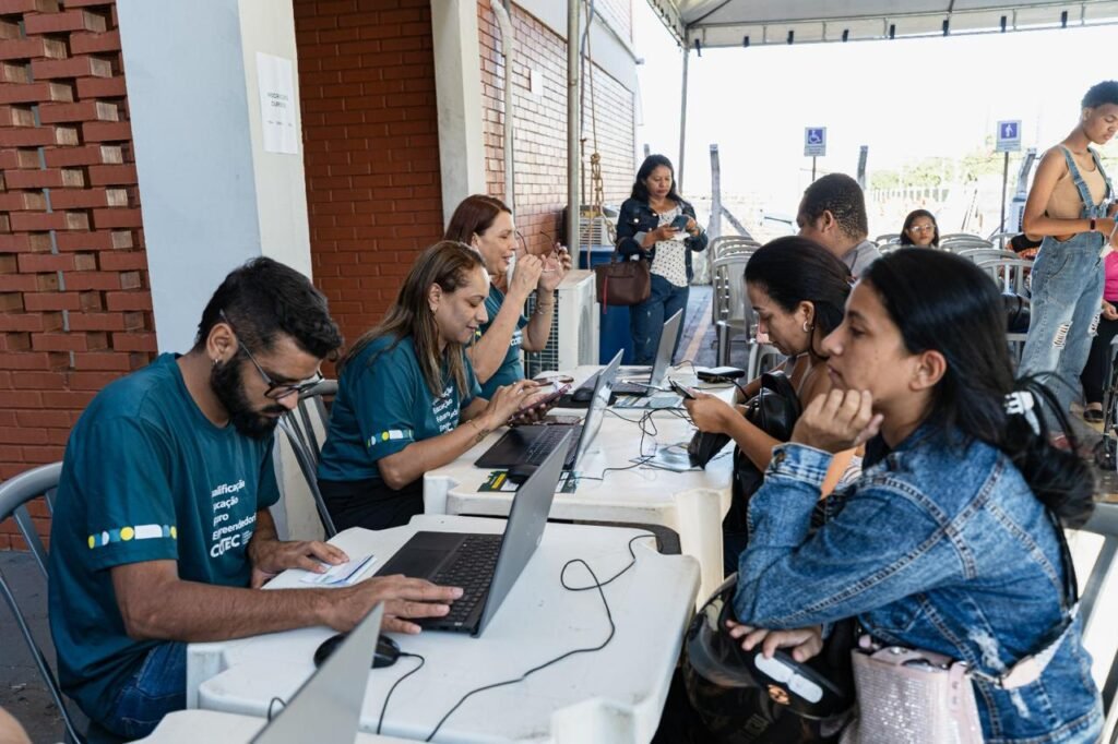 Equipe do Cotec atende candidatos em mesas com notebooks durante feirão de empregos em Goiânia