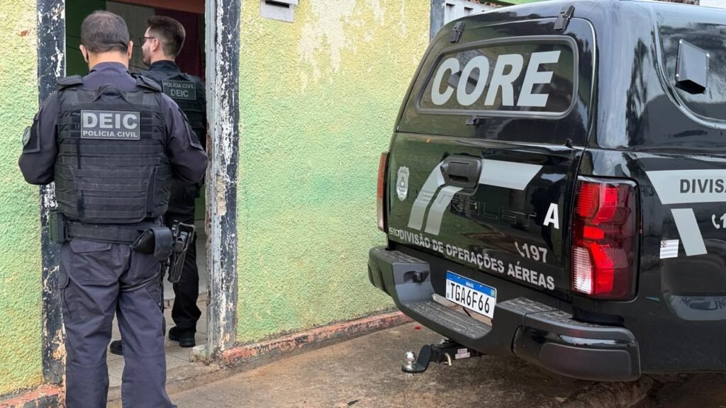 Agentes da Polícia Civil próximos a veículo policial durante cumprimento de mandados na Operação Destroyer