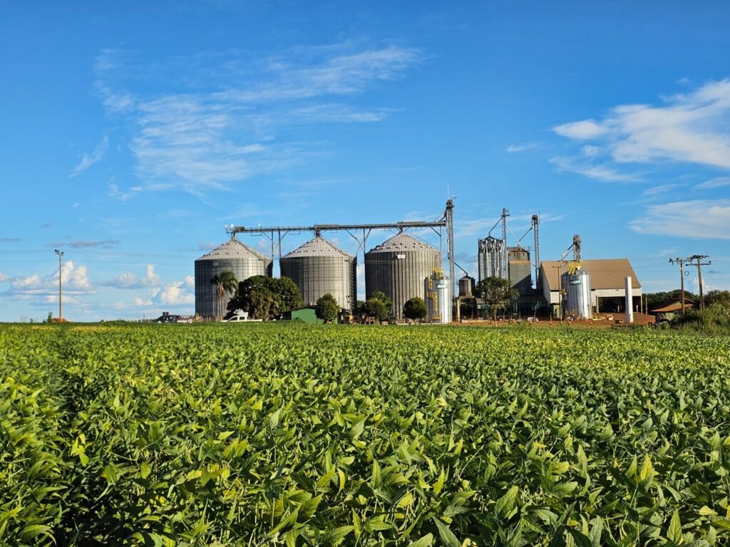 Lavoura de soja verde em Goiás com silos de armazenagem ao fundo